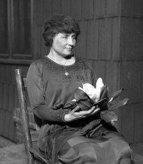 Helen Keller sitting holding a magnolia flower, circa 1920 (Presumed Public Domain, from Los Angeles Times photographic archive, UCLA Library)